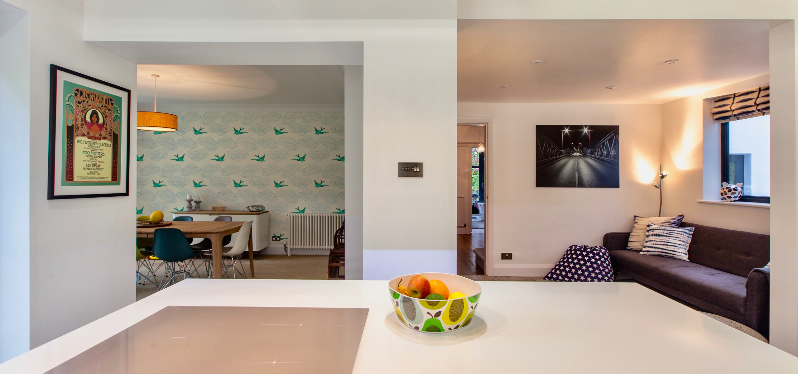 View from modern open plan kitchen island looking into dining area and sofa seating space