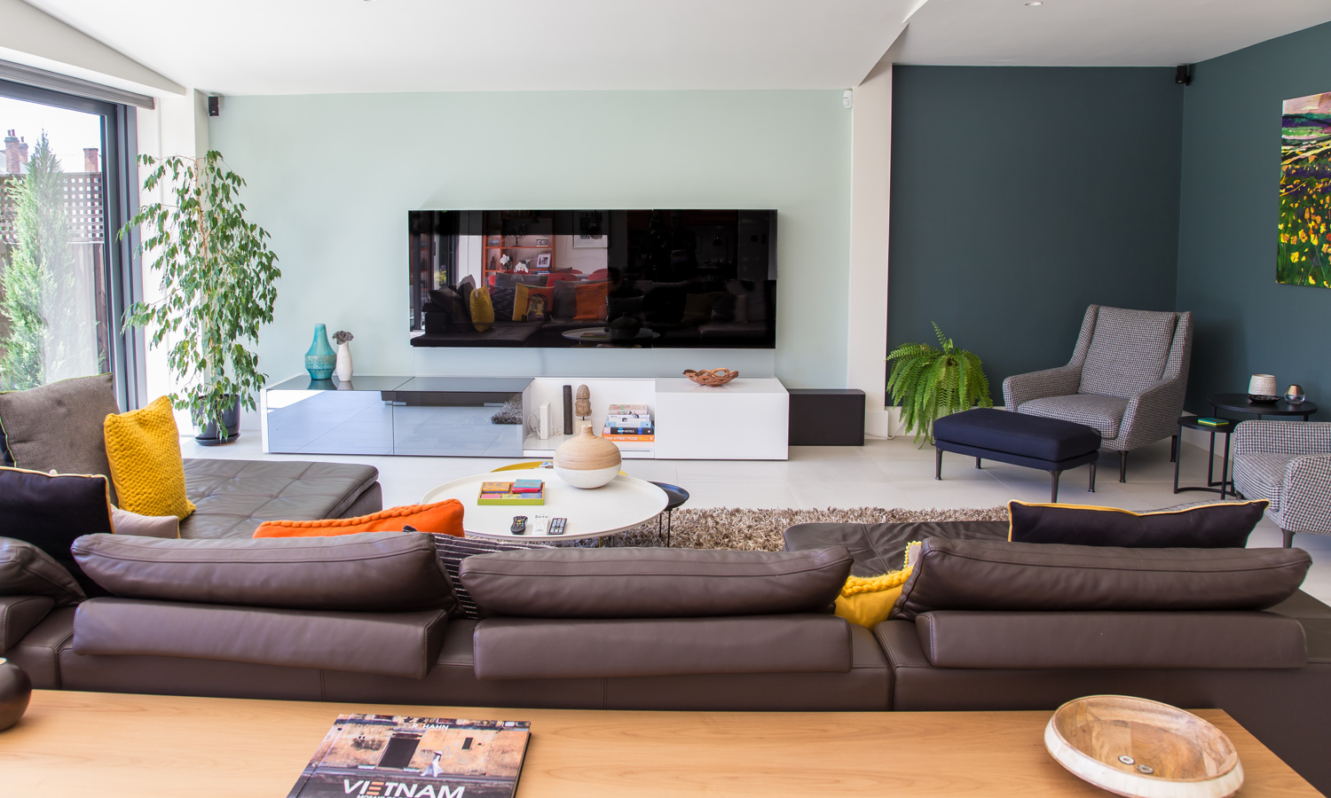 Modern living room with soft blue and teal walls, brown sofa and contemporary furniture