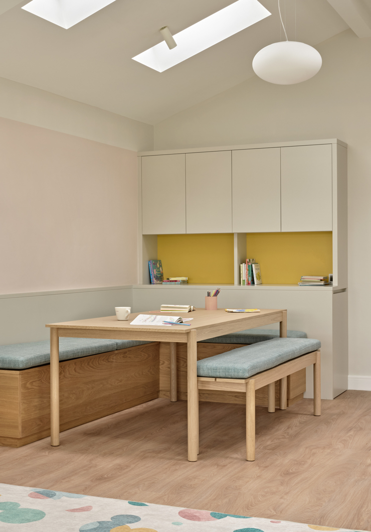 Modern playroom fitted bespoke joinery with storage fitted bench and table in beige yellow pink and blue