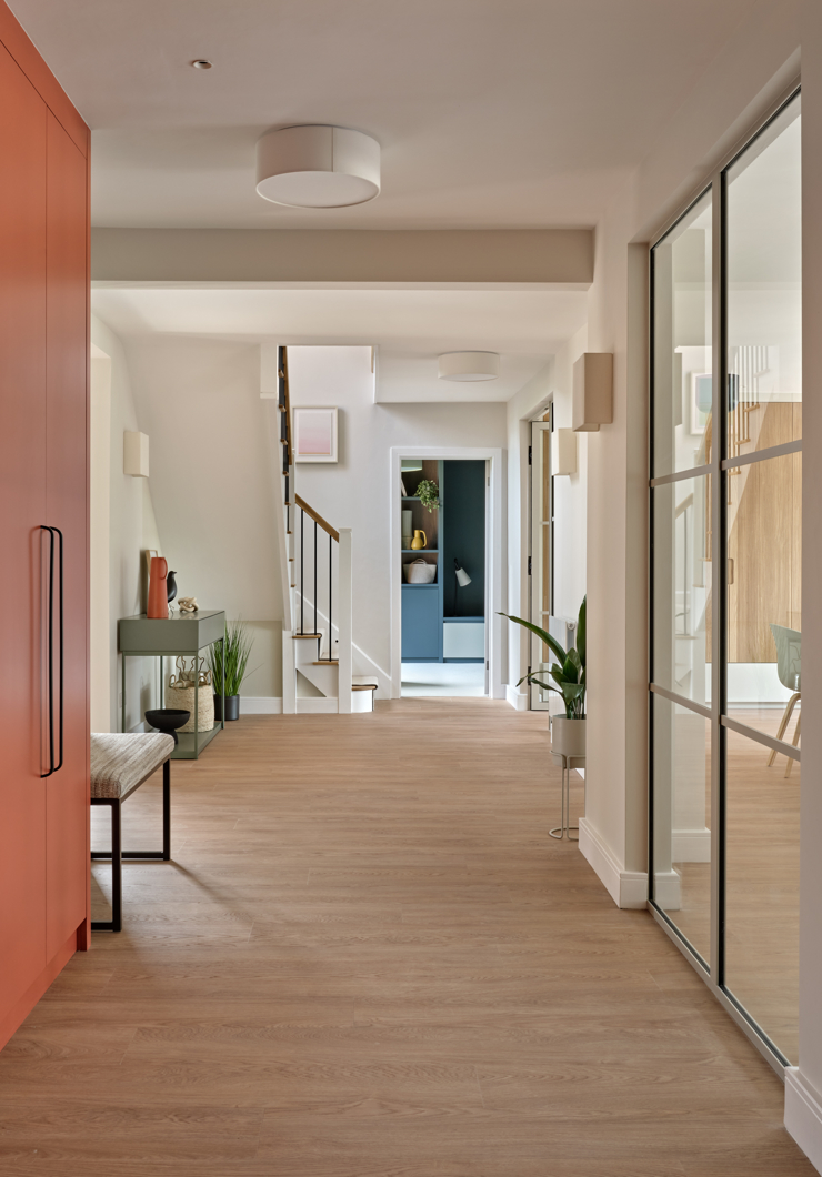 Hallway with oak coloured floor, red fitted cupboards, and internal glazed screens