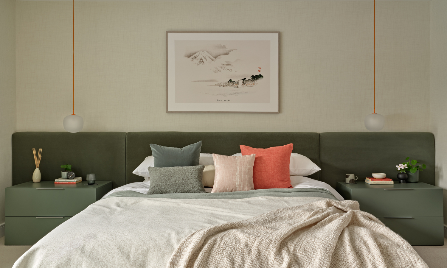 Wall to wall upholstered smooth velvet headboard and bed in dusty green with contemporary pendant bedside lights and green low bedside draweres