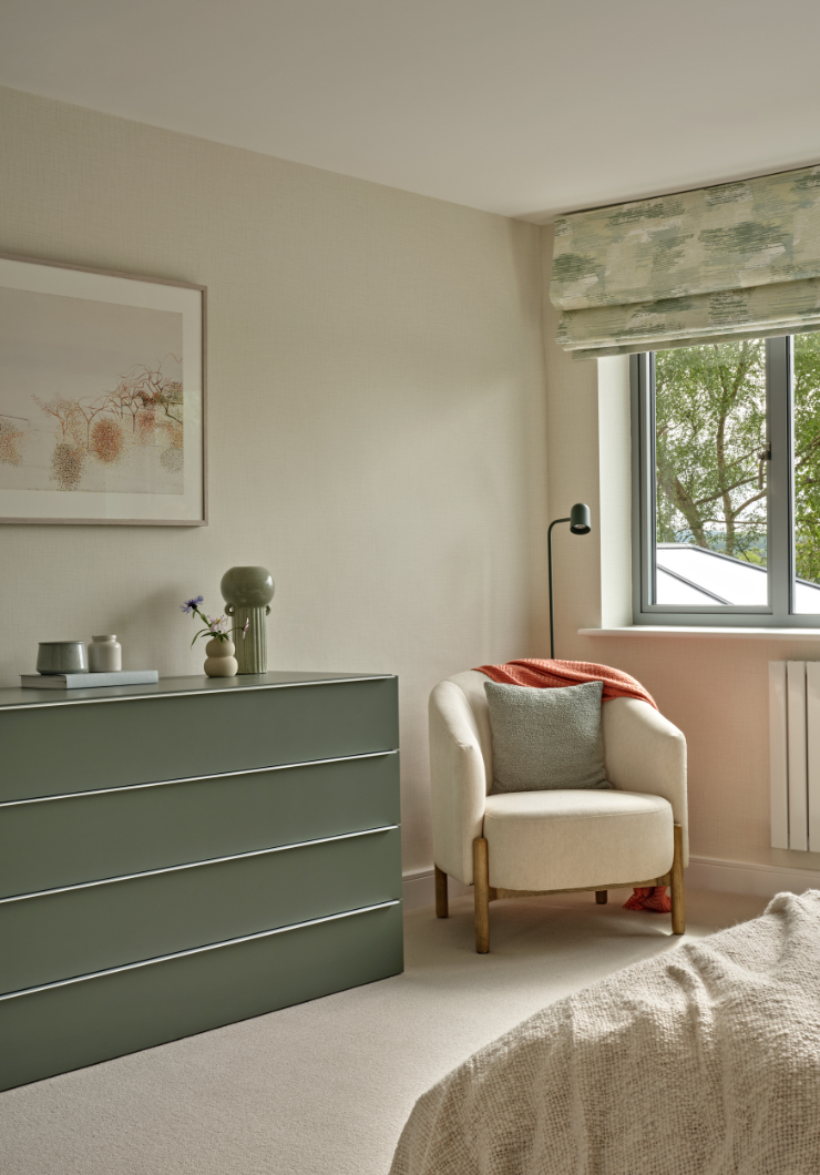 Dusty green and beige master bedroom with contemporary chest of drawers roman blind and armchair